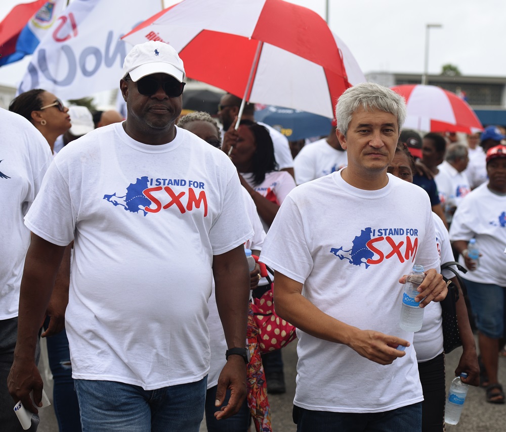 Protesters delivered signed petitions to various government offices on Wednesday, Aug. 29, condeMember of Parliament Theo Heyliger, representing United Democrats, and former Minister and MP Frankie Meyers, also of UP, walk among fellow protesters.