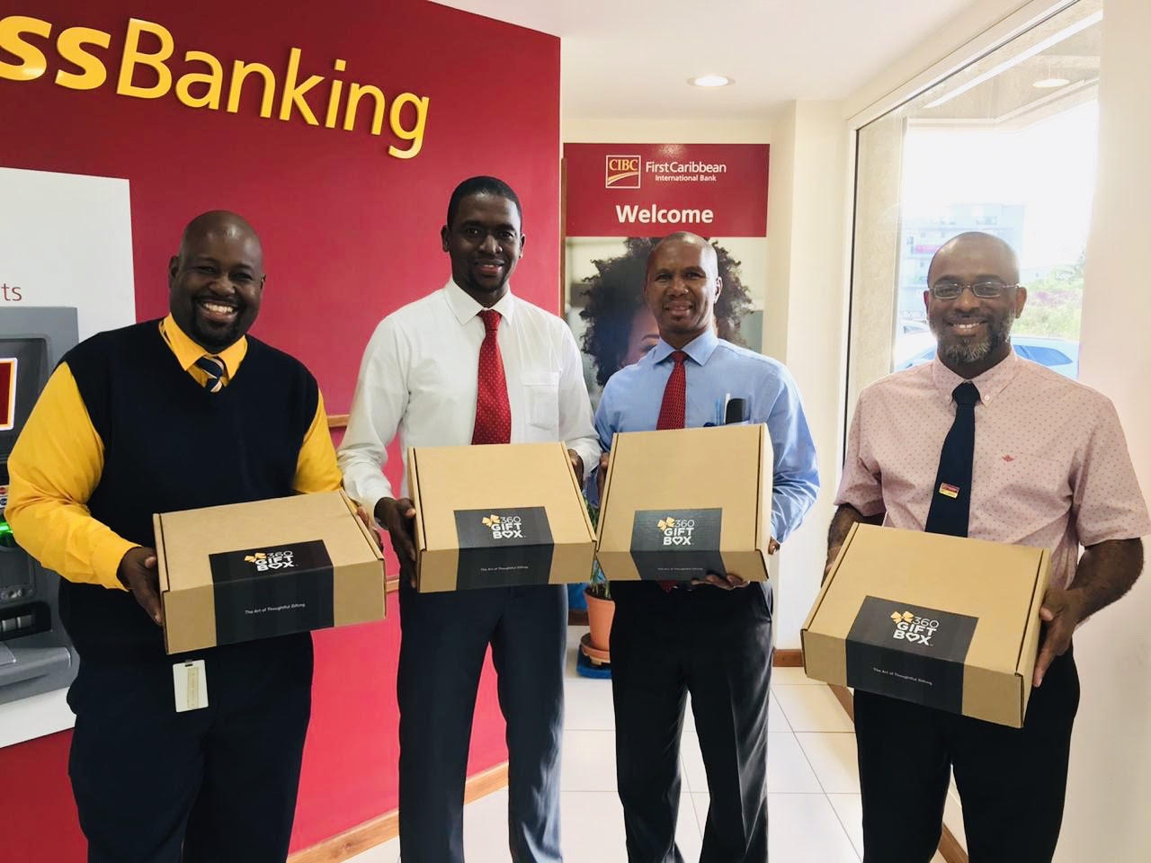 Male staff members at CIBC FirstCaribbean Cole Bay Branch receiving gifts of appreciation for their positive contributions. - Men's